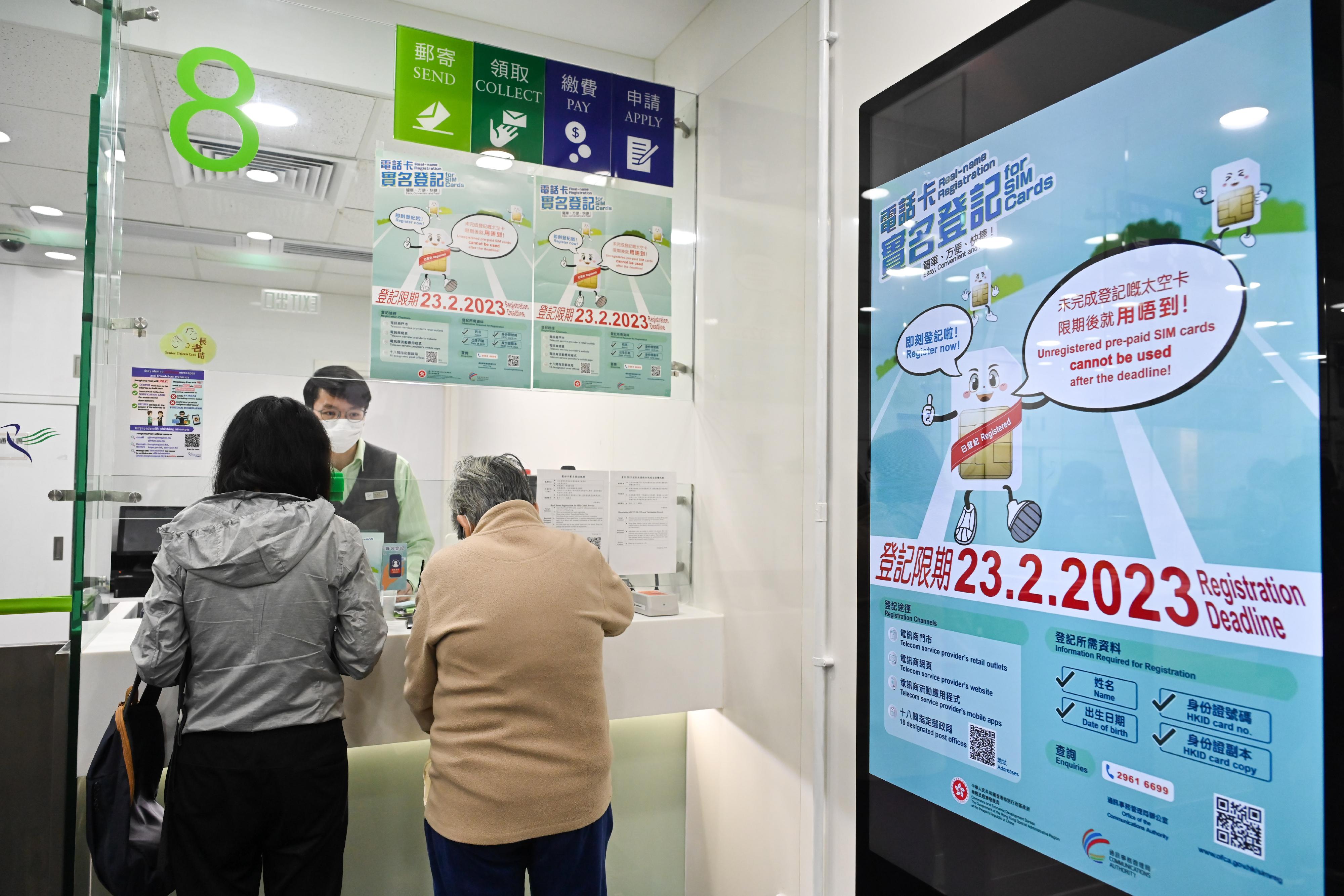 為協助市民於下周四（二月二十三日）前盡快完成電話卡實名登記，政府加強宣傳和支援服務。圖示其中一間指定郵政局內的服務櫃位人員協助市民進行登記。