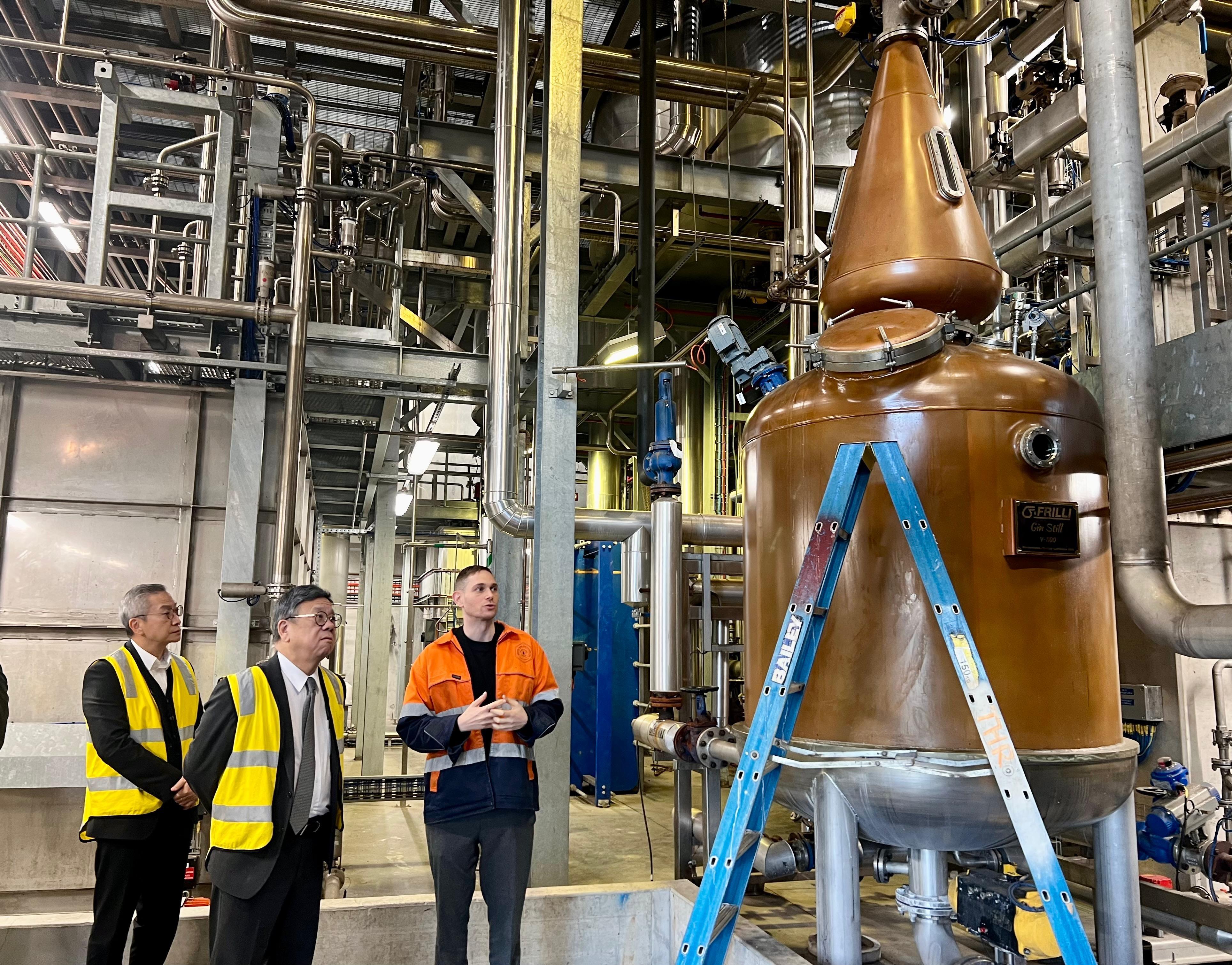 商务及经济发展局局长丘应桦今日（八月十五日）在澳洲悉尼进行最后一日访问。图示丘应桦（中）到访一间蒸馏厂，了解蒸馏过程和澳洲烈酒的发展。旁为香港驻悉尼经济贸易办事处处长庄国民（左）。